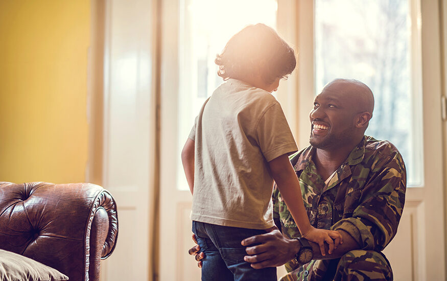 Military father in uniform smiling at young child