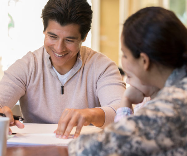 young man smiling and speaking to service women and young child