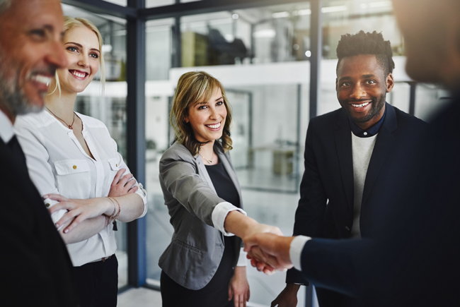 employees shaking hands and smiling at each other in office