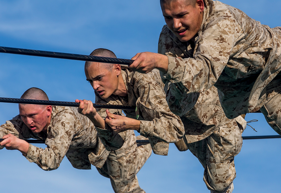 Military service members climbing across ropes