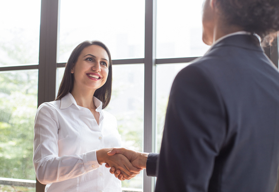 Cheerful confident female manager concluding deal with handshake