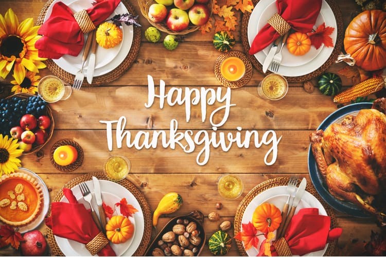 Thanksgiving dinner laid out on the wooden dinner table. “Happy Thanksgiving” written in white text in the center of the image.