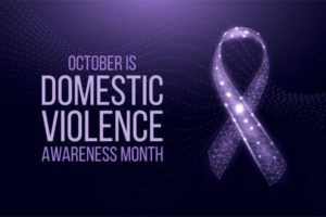 Purple ribbon with sparkles on dark purple background, “October is Domestic Violence Awareness Month".